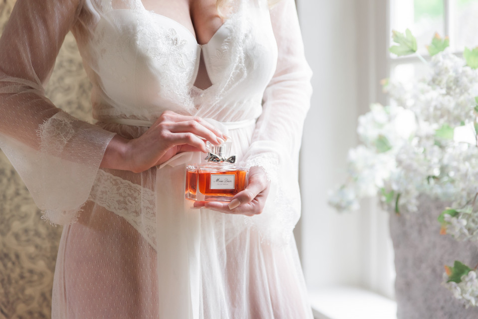 een vrouw in een witte badjas die een parfumfles vasthoudt