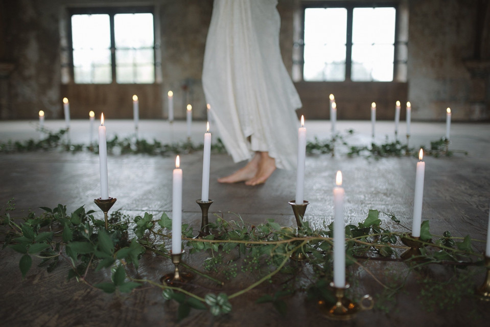 een vrouw in een witte jurk die voor kaarsen staat