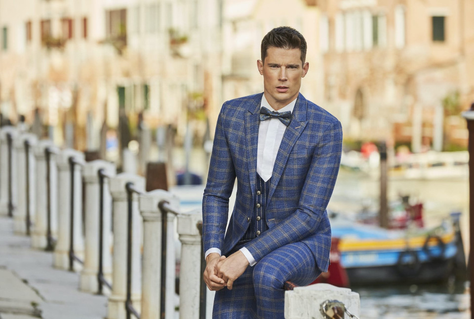 een man in een blauw pak en strik zit op een reling