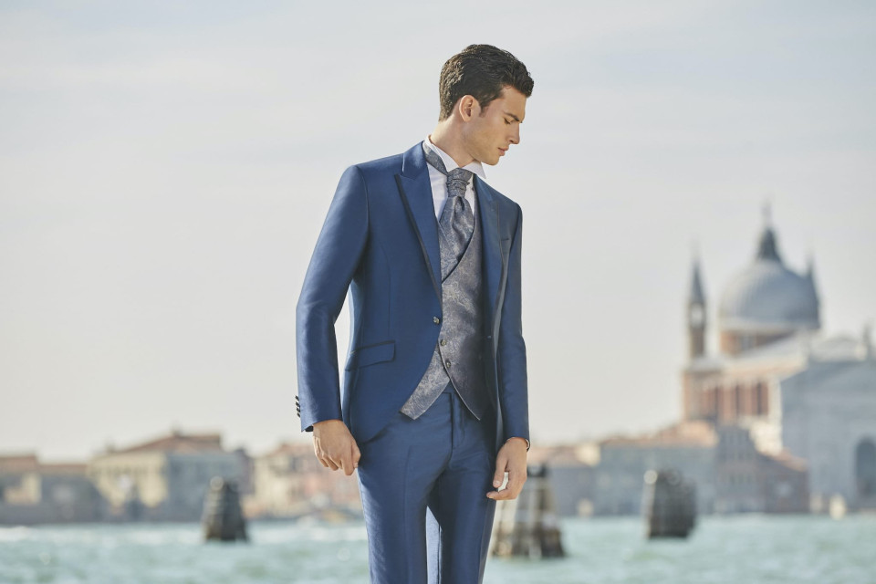 een man in een blauw pak en stropdas staat op een dok