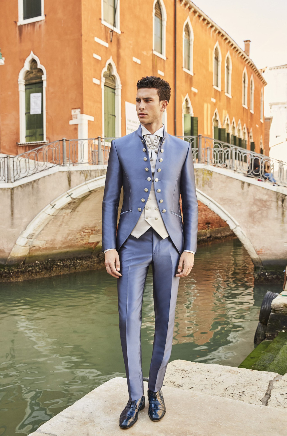 een man in een blauw pak staat op een brug