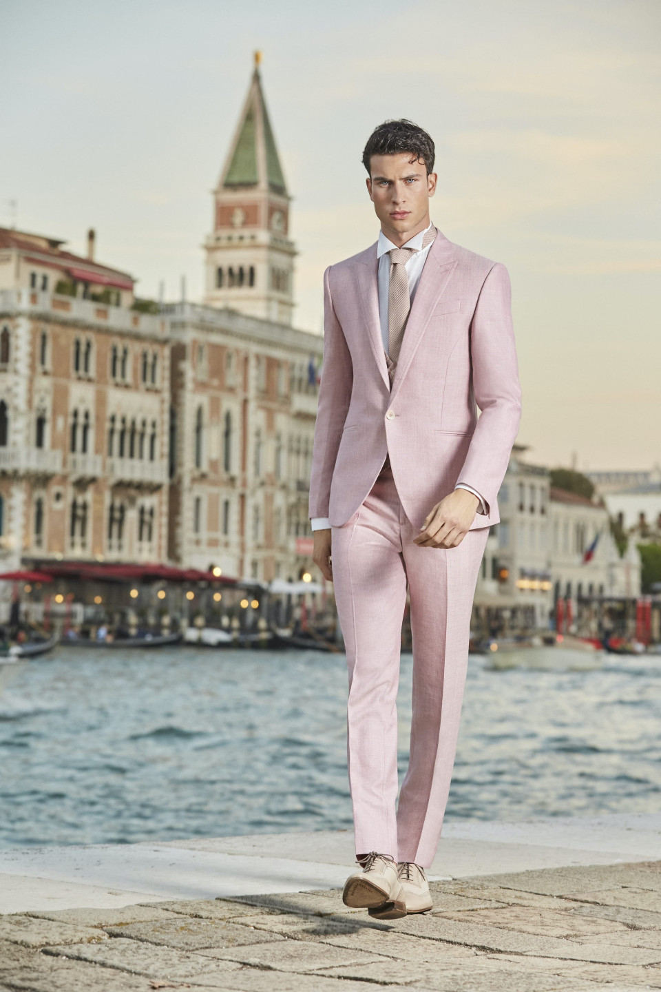 een man in een roze pak loopt langs het water