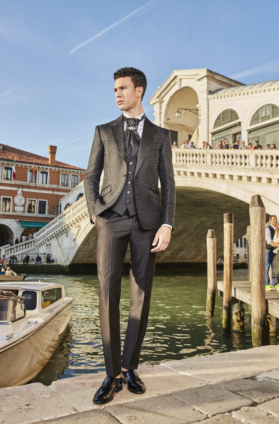 een man in een pak staat op een dok naast een gracht