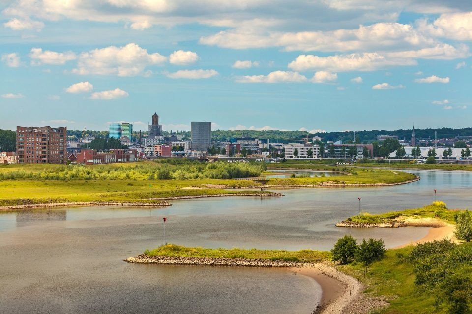 een rivier die door een grasveld stroomt met gebouwen op de achtergrond