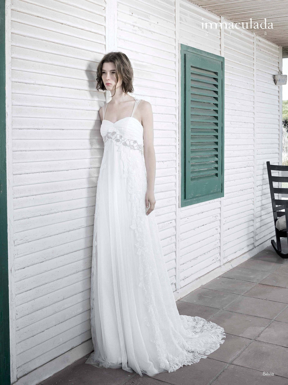 een vrouw in een trouwjurk leunend tegen een muur