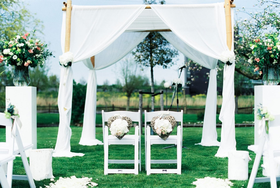 buitenceremonie met witte stoelen en bloemen