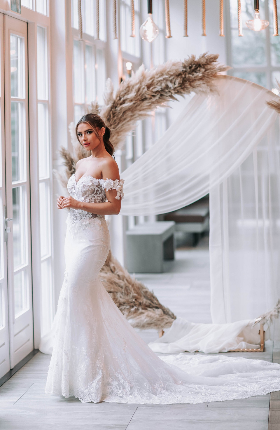 een bruid in een trouwjurk die poseert voor een grote witte boog