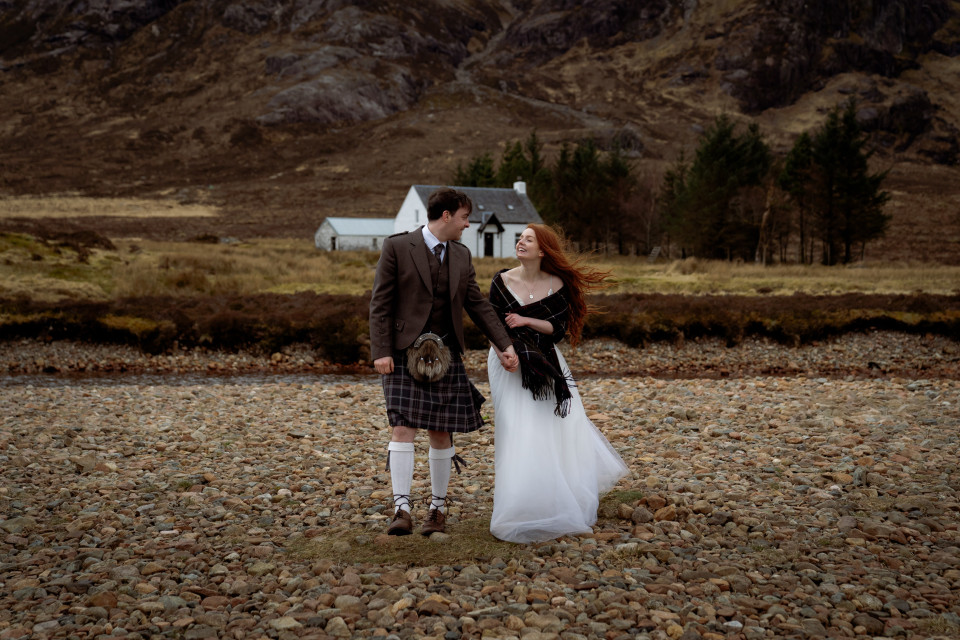 een bruid en bruidegom in kilts staan op rotsen voor een berg