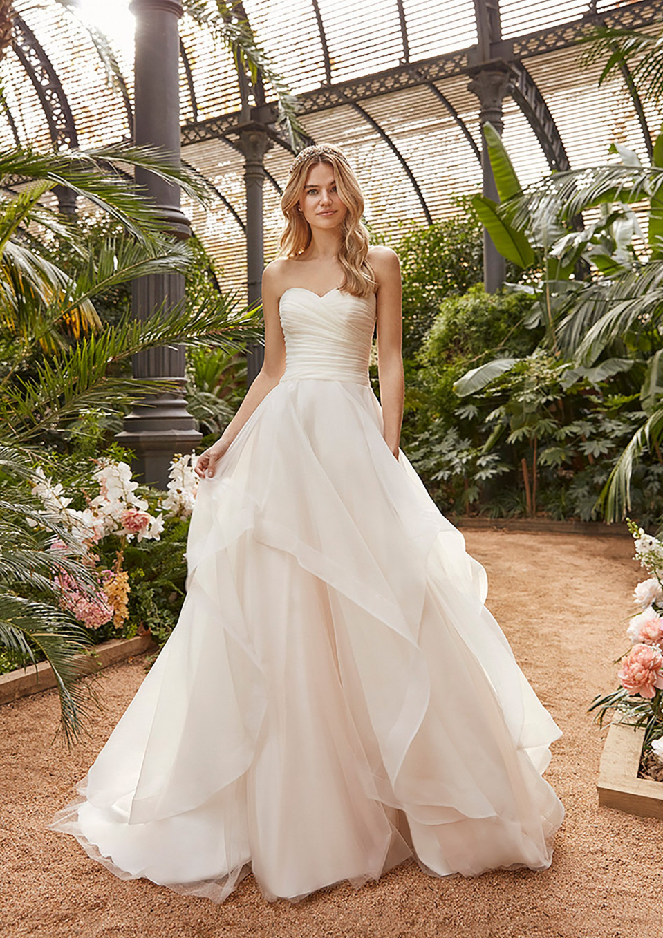 een mooie vrouw in een strapless trouwjurk die in een tuin staat