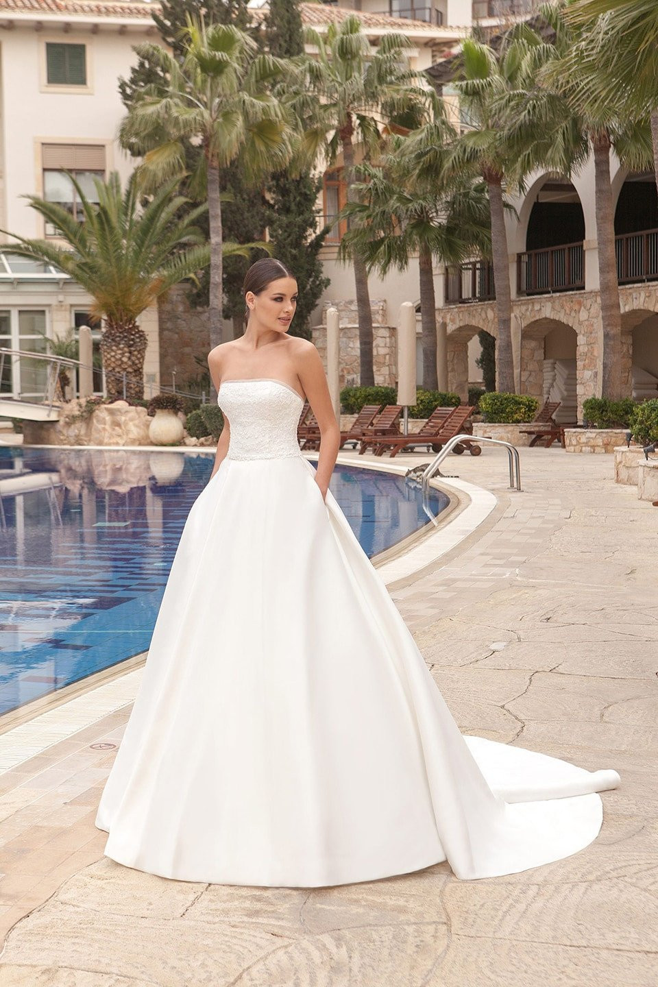 een vrouw in een strapless trouwjurk bij het zwembad