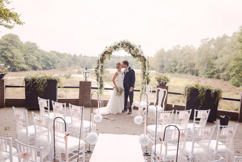 een bruid en bruidegom kussen onder een doorgang