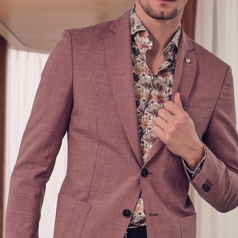 een man in een roze pak en bloemenoverhemd