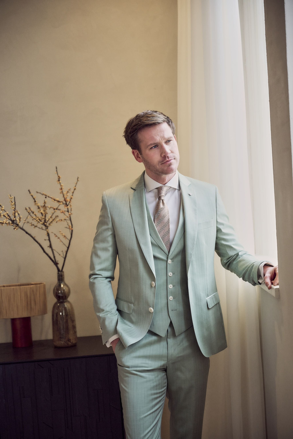 een man in een muntgroen pak en stropdas