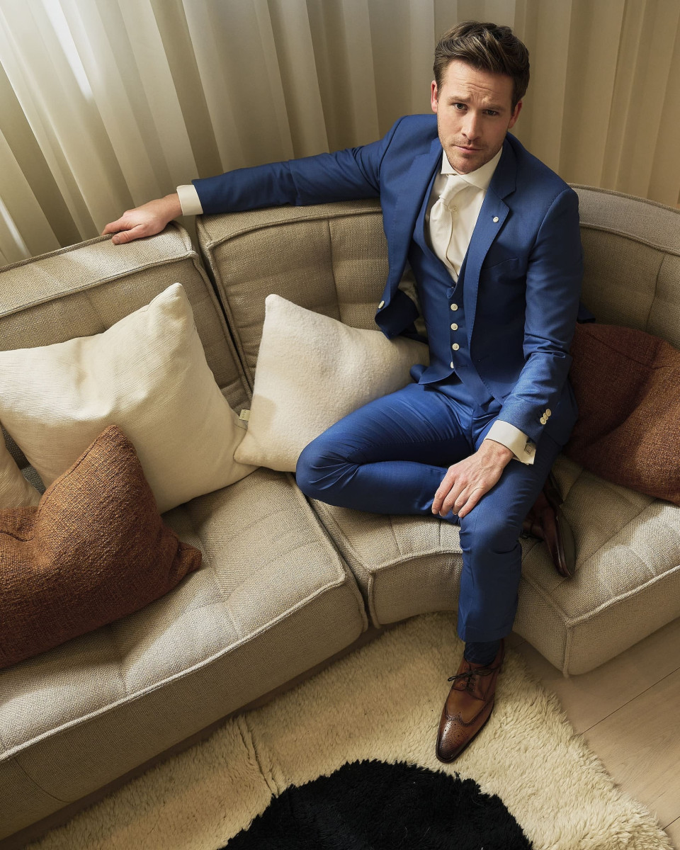 een man in een blauw pak die op een bank zit