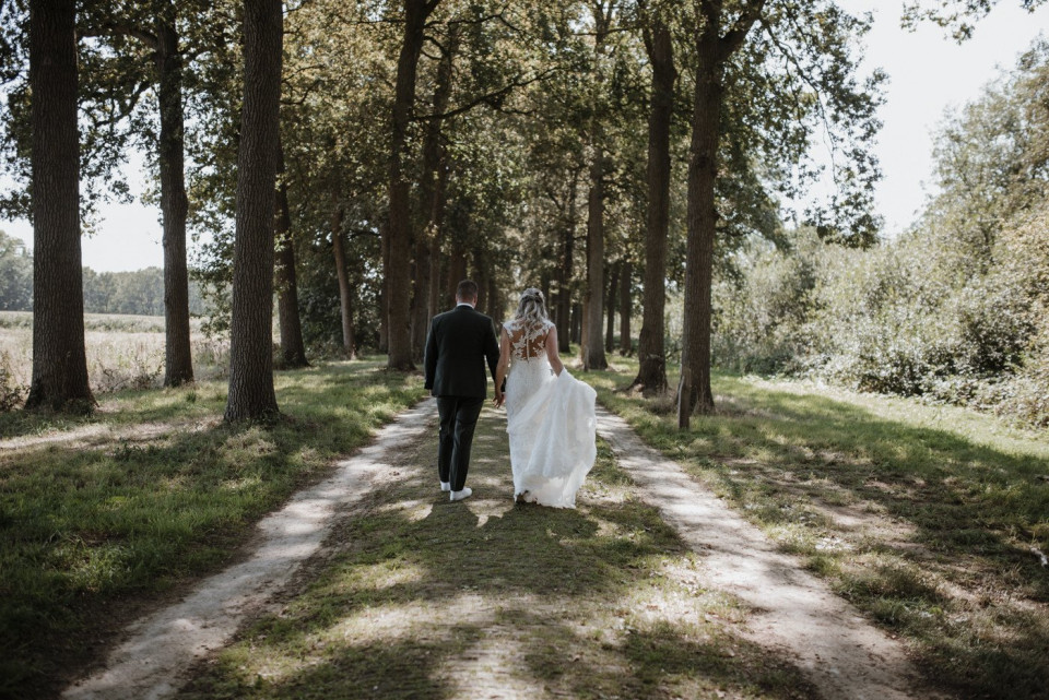 een bruid en bruidegom lopen op een pad in het bos