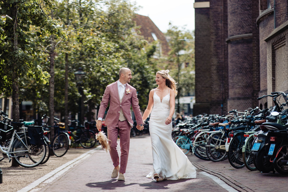 een bruid en bruidegom lopen een straat in met fietsen