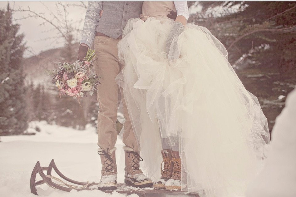 een bruid en bruidegom staan op een slee in de sneeuw