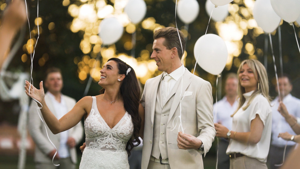 een bruid en bruidegom houden witte ballonnen vast