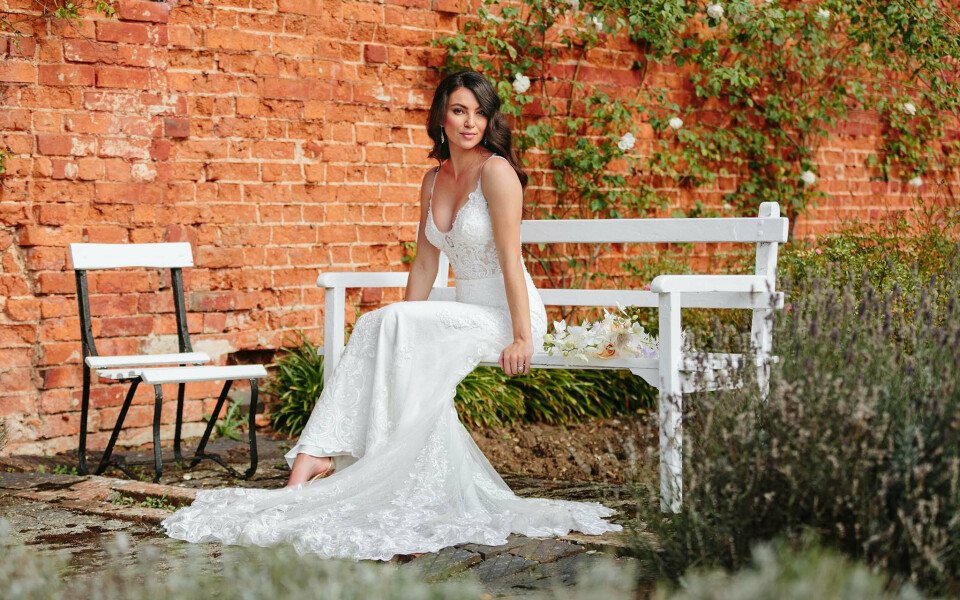 een vrouw in een trouwjurk zittend op een bank