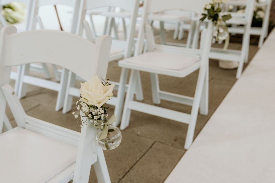 een rij witte stoelen met bloemen erop