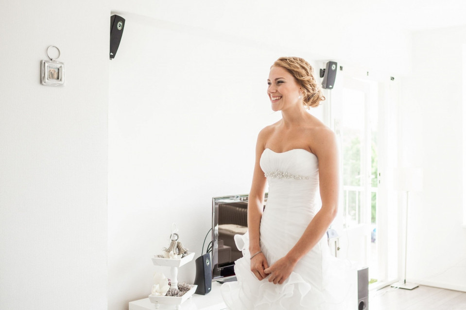 een mooie bruid in een witte jurk die in een kamer staat