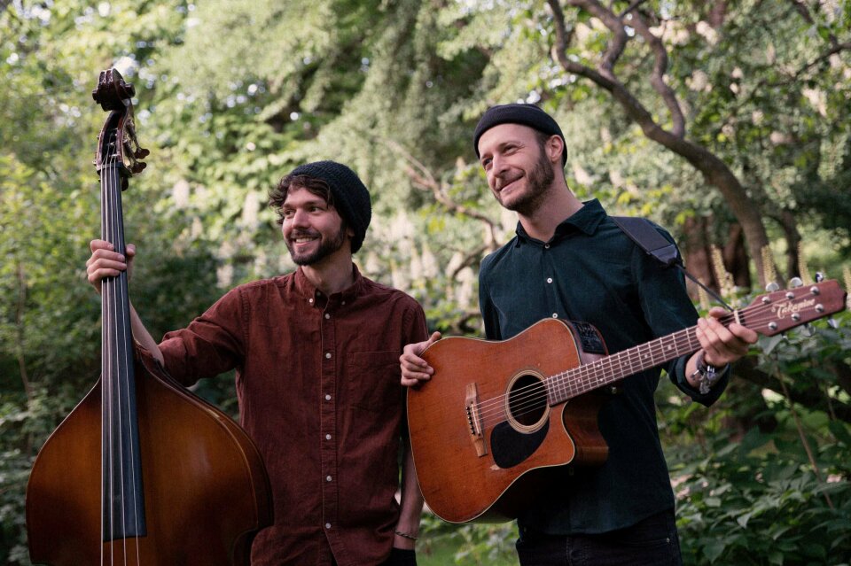 een man met een gitaar en een bas die naast elkaar staan