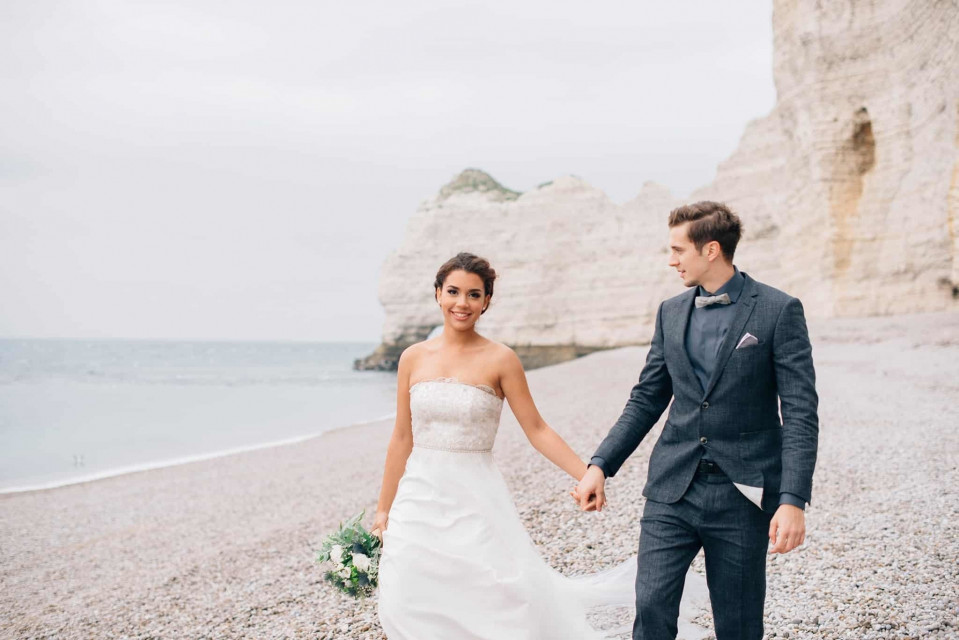 bruid en bruidegom lopen op het strand bij kliffen