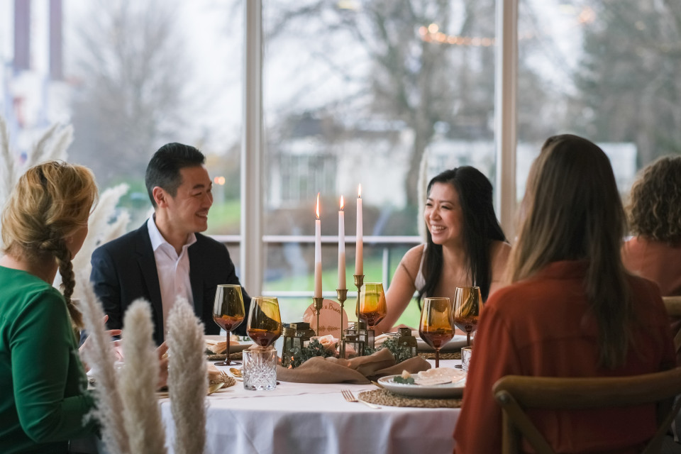 een groep mensen zit aan tafel met kaarsen