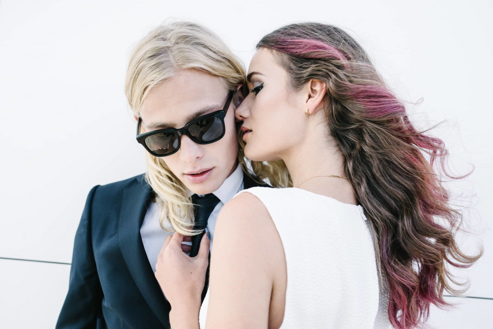 een vrouw in pak en zonnebril kust een man