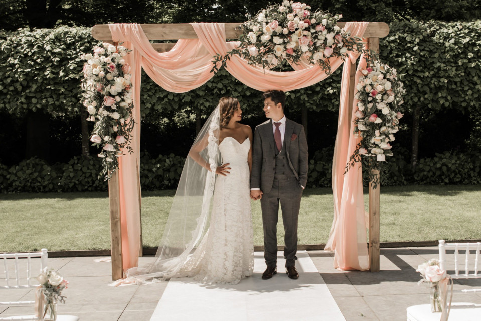 bruiloftsceremonieboog in roze en perzik