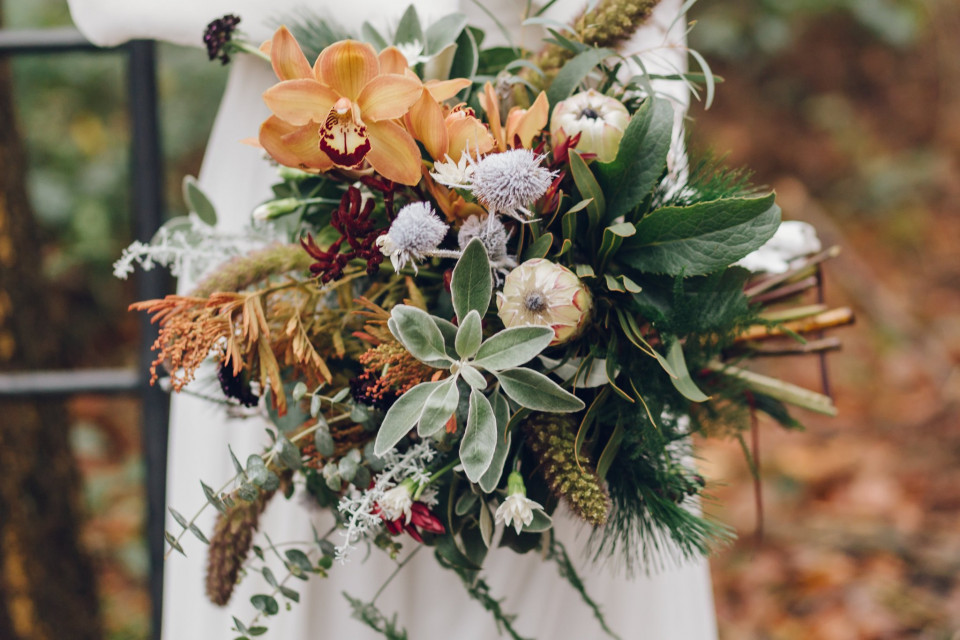 een bruid die een boeket bloemen vasthoudt in het bos