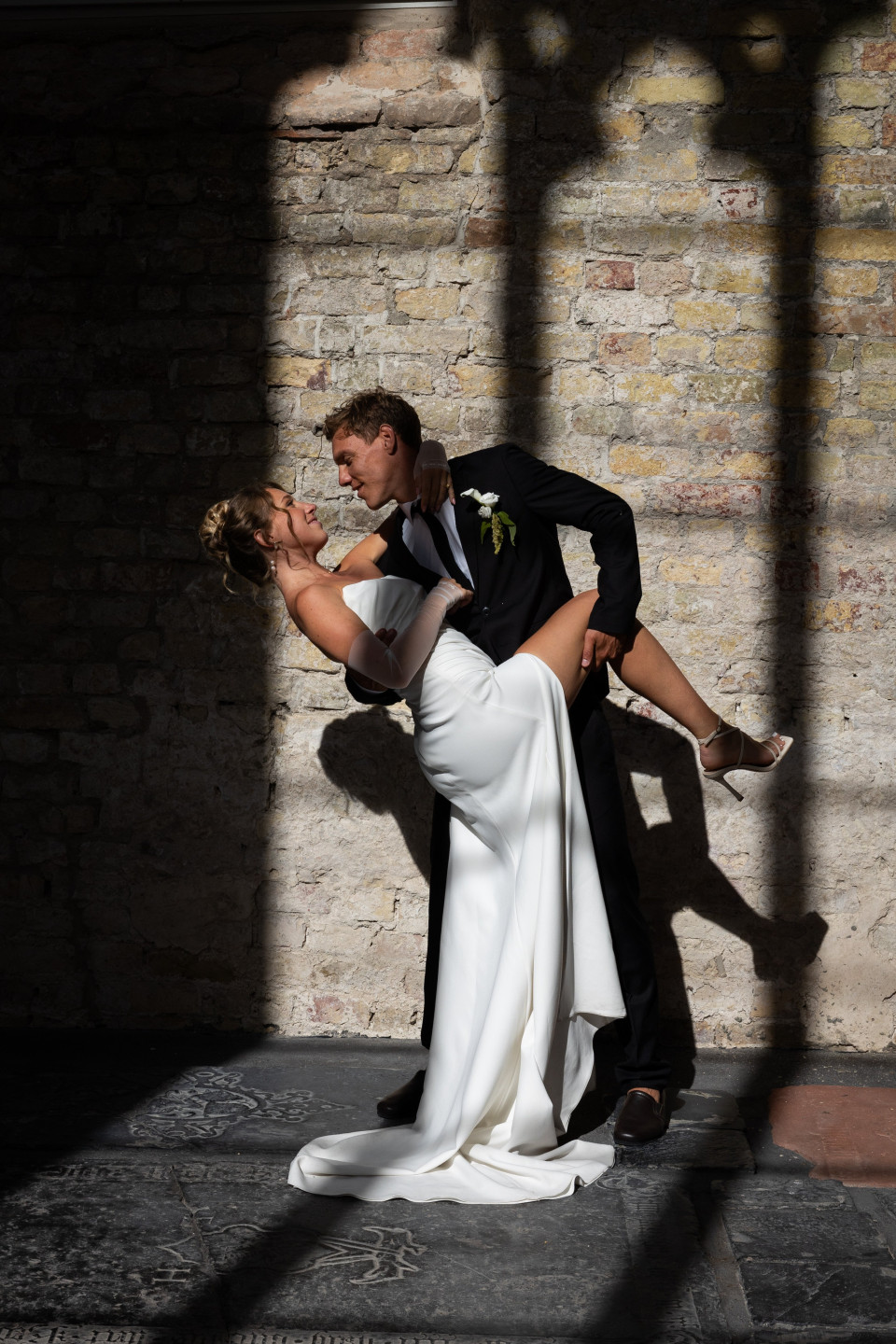 een afbeelding van een bruid en bruidegom die kussen in het zonlicht