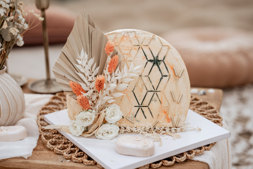een tafel met een witte taart, bloemen en een kaars