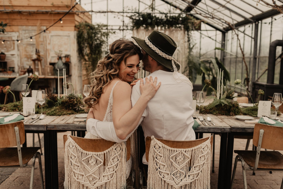 de bruid en bruidegom zitten aan tafel in de kas