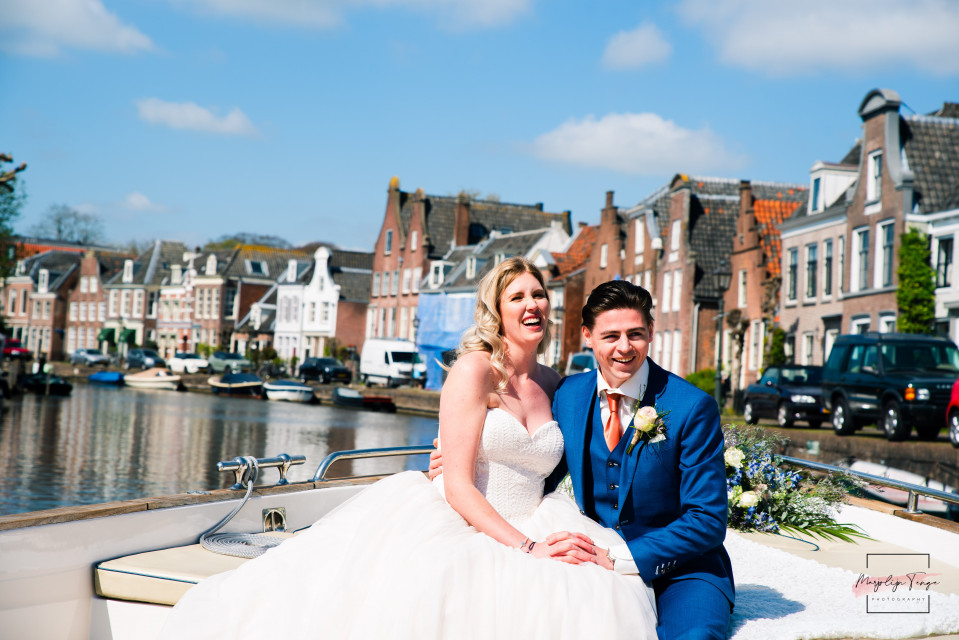 een bruid en bruidegom zitten op een boot voor een gracht