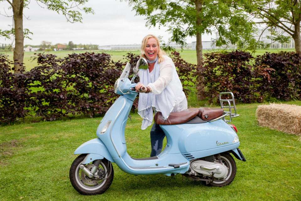 een vrouw zit op een blauwe scooter