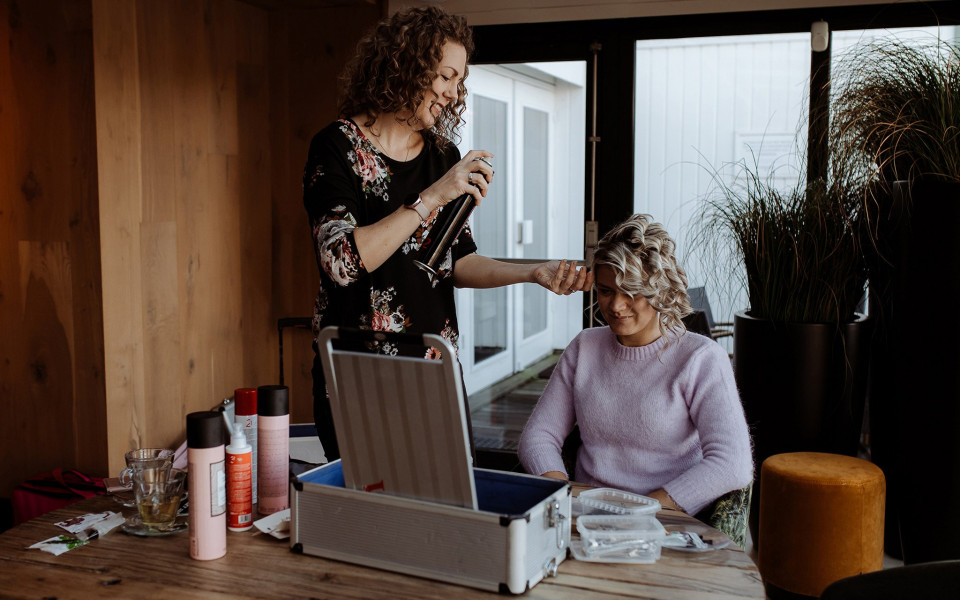 een vrouw die haar haar laat doen door een andere vrouw