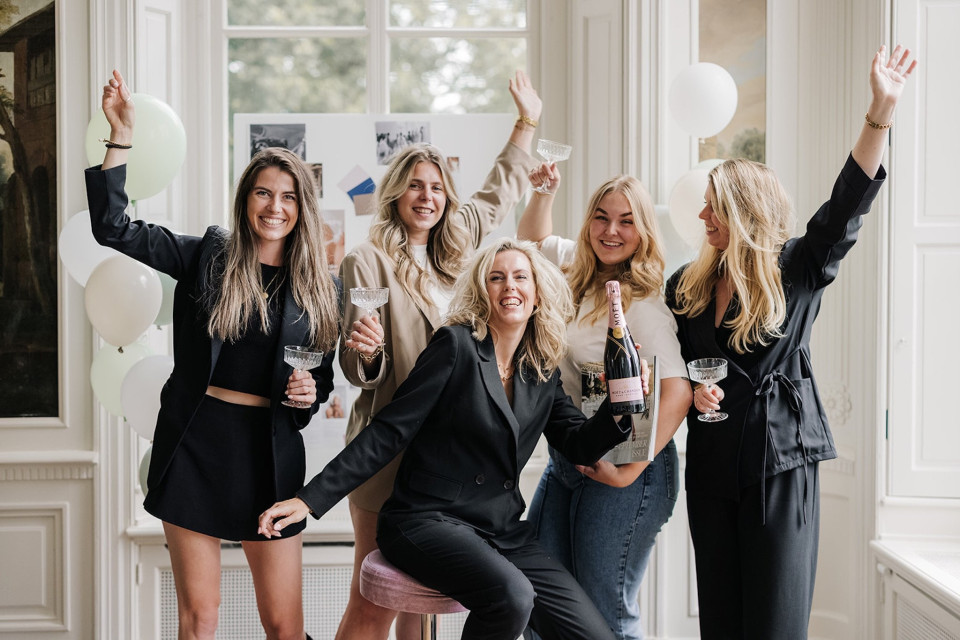 een groep vrouwen die poseren voor een foto met champagne en ballonnen