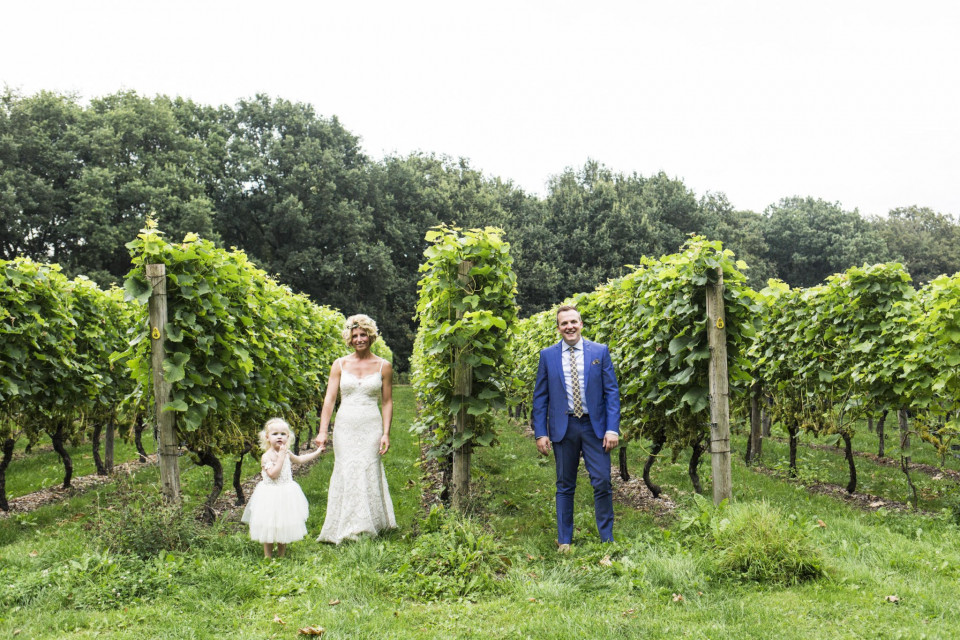 een bruid en bruidegom en hun dochter in de wijngaard