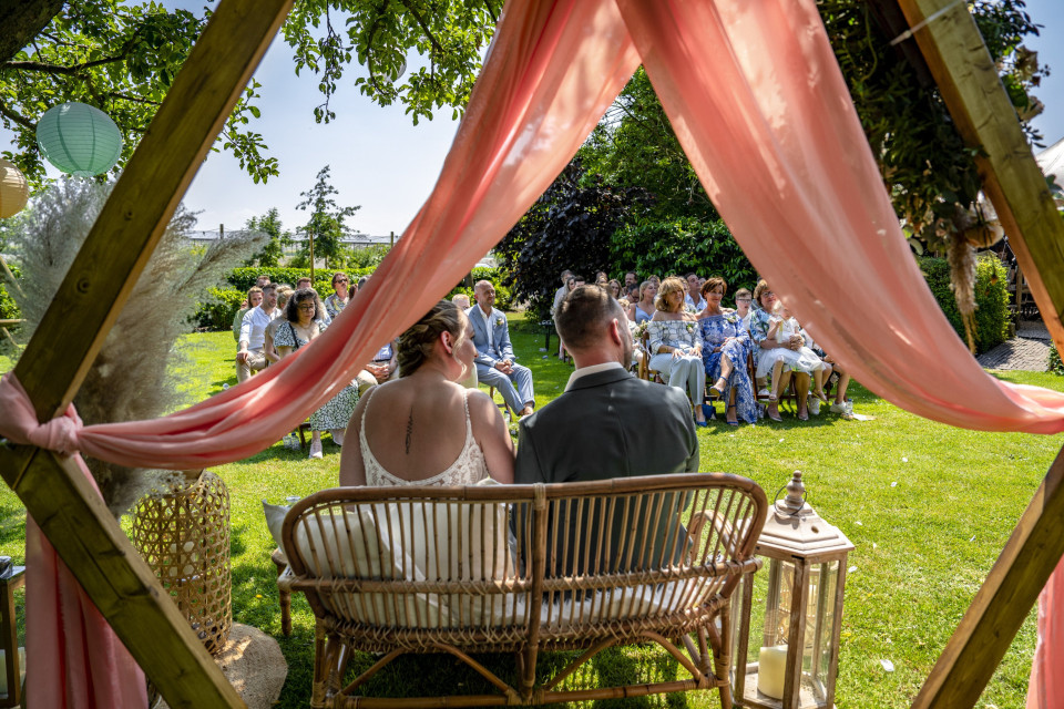 een bruiloftsceremonie in de tuin met roze gordijnen