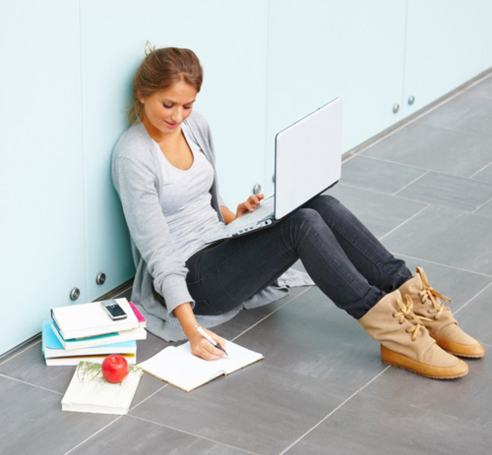 een jonge vrouw zit op de grond met haar laptop