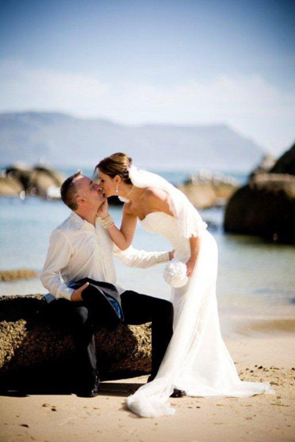 een bruid en bruidegom die kussen op het strand
