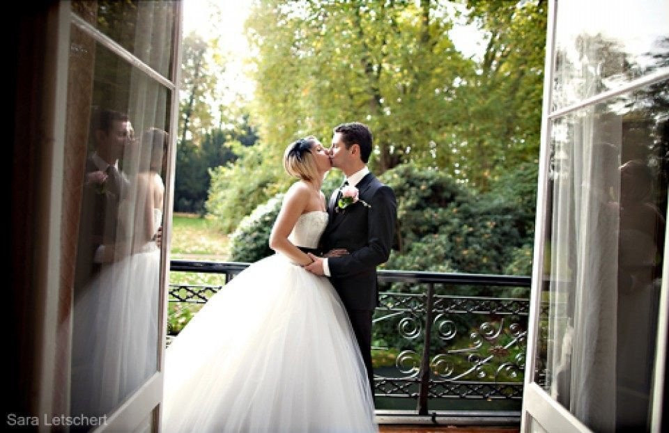een bruid en bruidegom kussen voor een open deur