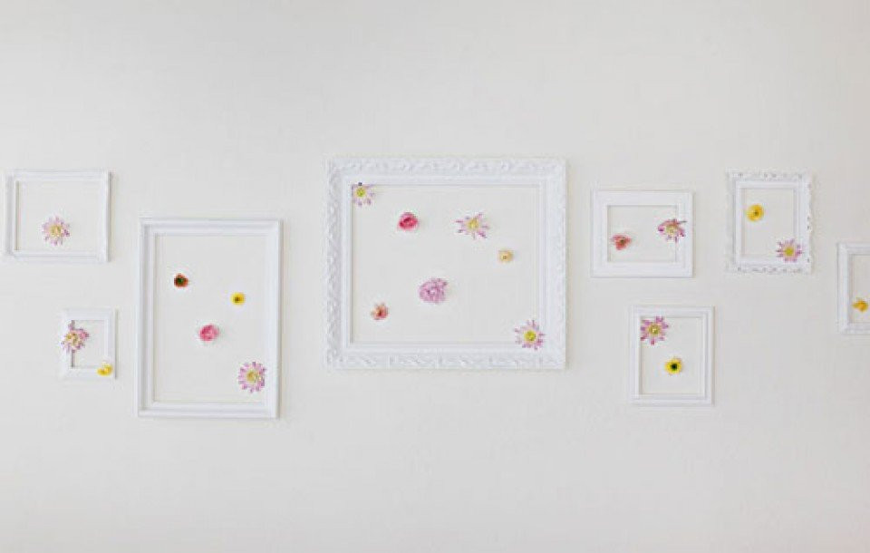 een witte muur met verschillende lijsten en bloemen