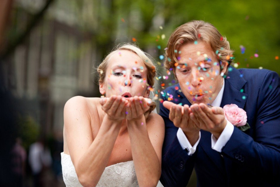 een bruid en bruidegom die confetti op elkaar blazen