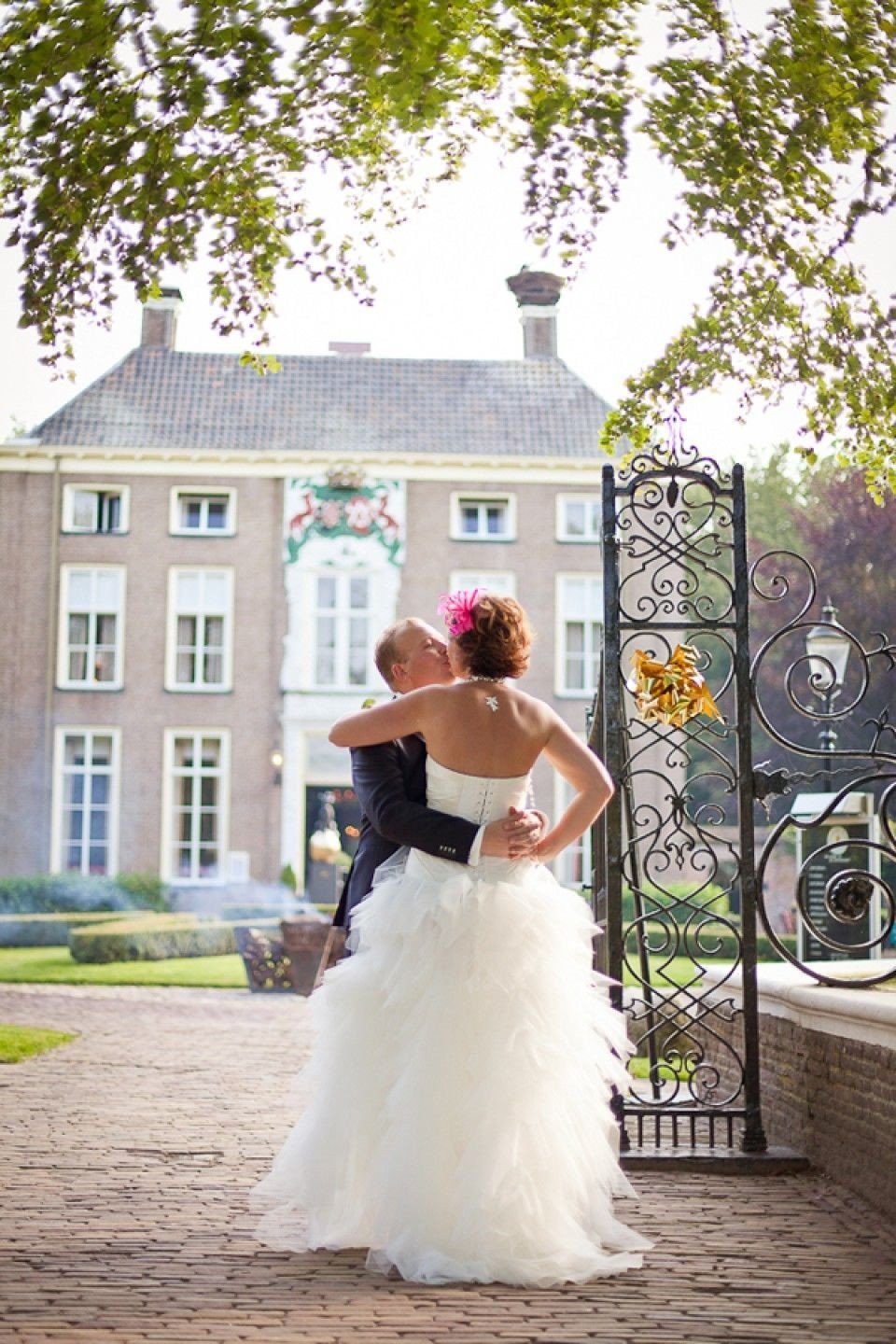 een bruid en bruidegom omhelzen elkaar voor een groot landhuis