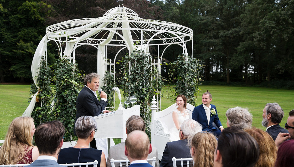 een bruiloftsceremonie in het park met een prieel