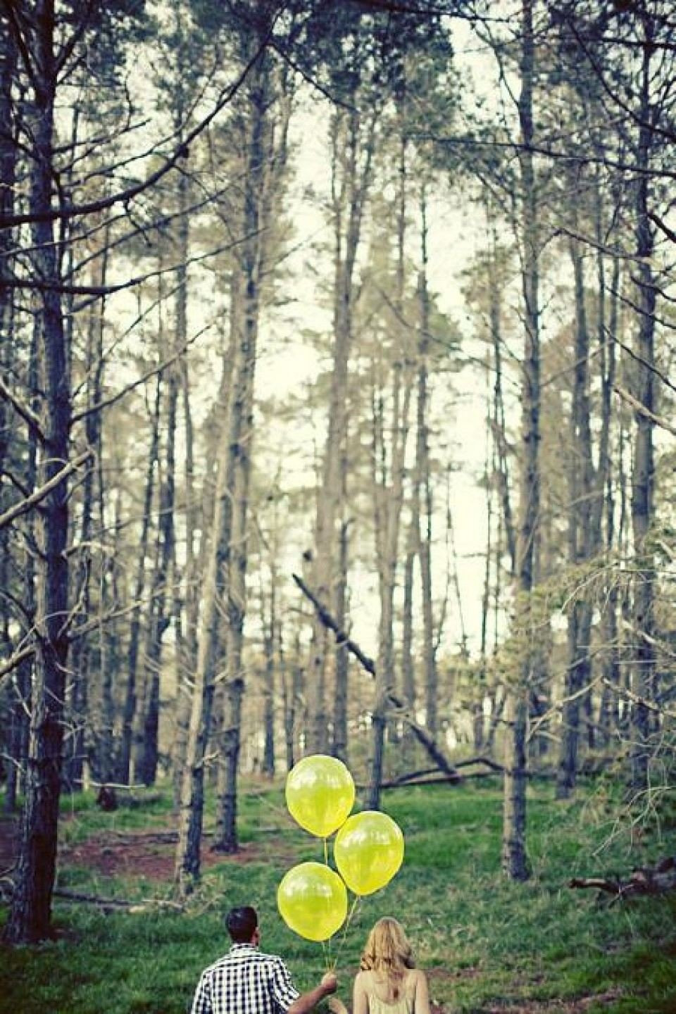 een stel dat gele ballonnen vasthoudt in het bos