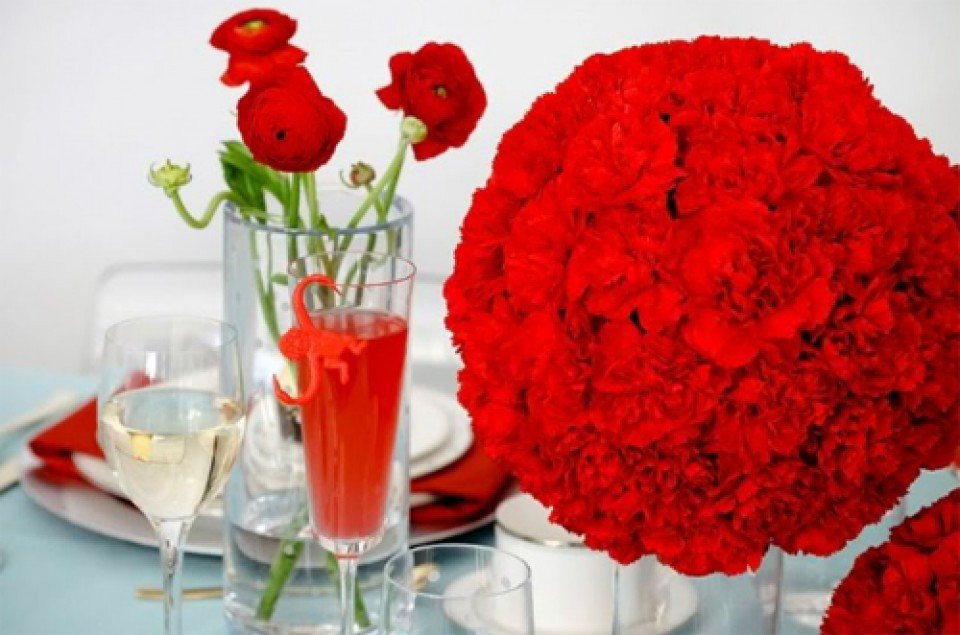 een tafel met rode bloemen en champagneglazen