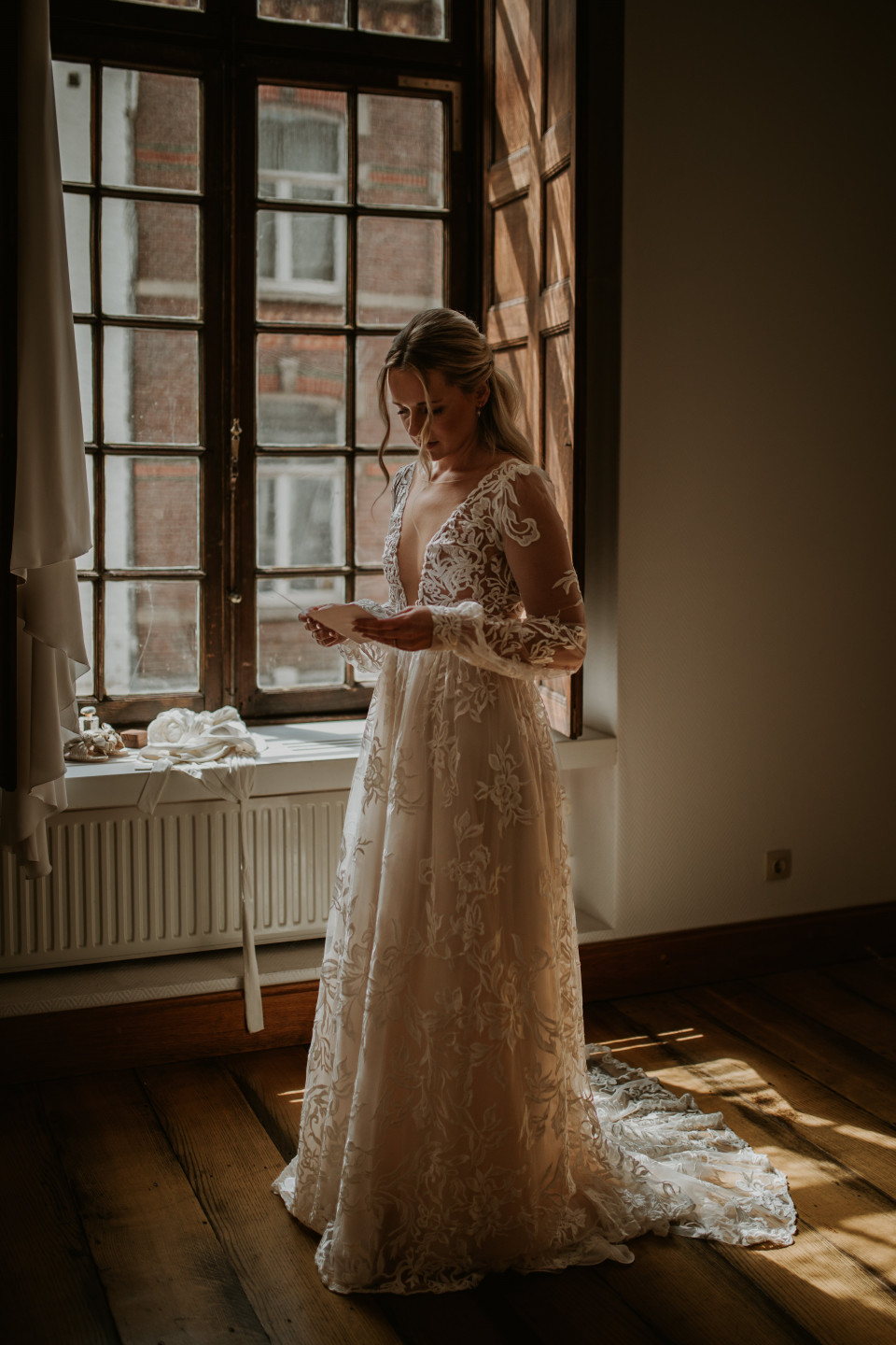 bruid in trouwjurk voor het raam